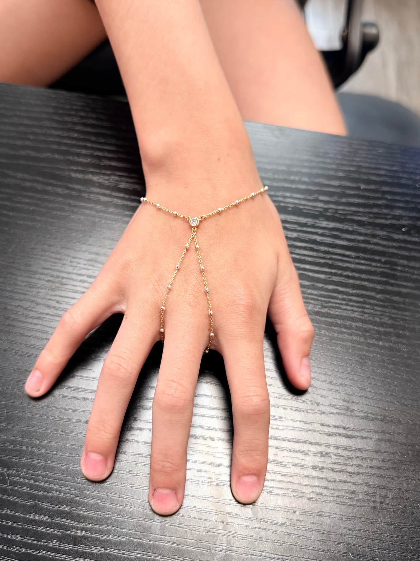Gold beaded hand chain with a stone